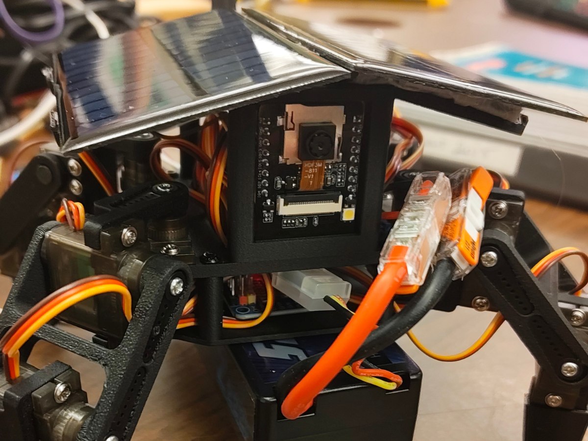 S.O.L.A.R. hardware close-up showing the ESP32-CAM, printed component interfaces, servo wiring, battery enclosure, connectors, and solar panels.